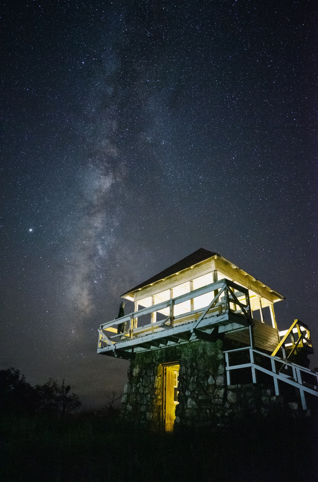 Girl looking at the Milky Way from an old fire tower
